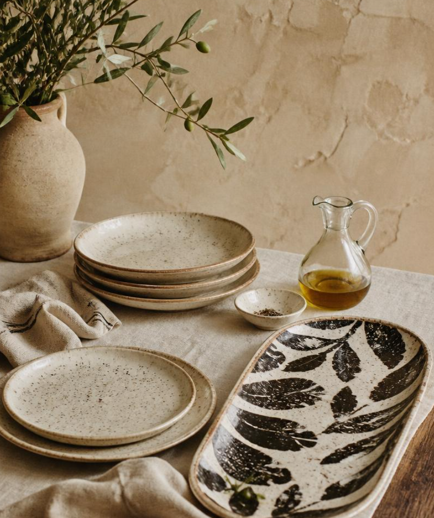 A long, curved ceramic serving platter with an organic black and off-white cow-print pattern, set against a solid red background.