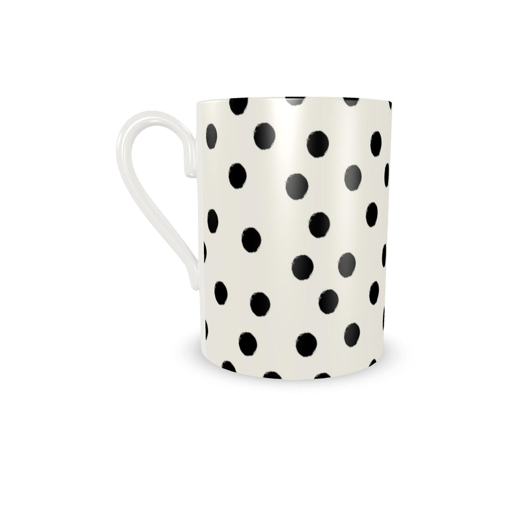 A white ceramic mug with a black polka dot pattern, shown on a clean white background.